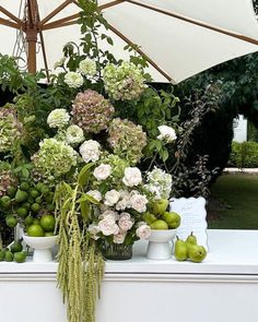 flowers and fruit are on display under an umbrella