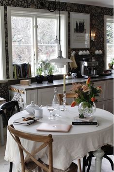 a kitchen with a table and chairs in front of two windows that have flowers on them