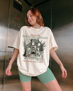 Countdown to Halloween with this exclusive Bookish Haunted Library Shirt. Perfect to be received as a thoughtful gift as well!  IMPORTANT (Please Read  Bookish merch exclusive from the Comfort Colors collection. .: 100% Cotton .: The soft-washed, garment-dyed fabric for an extra cozy feel. .: Medium fabric (6.1 oz/yd² (206.8 g/m .: Relaxed fit.  * CARE INSTRUCTIONS * ✺ Machine wash: cold (max 30C or 90F) ✺ Do not bleach. ✺ Tumble dry: Low heat. ✺ Iron, steam or dry: low heat ✺ Do not dry clean. * S I Z I N G * ✺ Please make sure to be accurate with your measurements before placing your order. For a more loose and comfortable fit, we suggest sizing up. * S H I P P I N G * T I M E S * ✺ Our items are individually made with love for each of our buyers. Delivery: Within 1 - 2 weeks (usually so Bookish Outfits, Bookish Shirts, Haunted Library, Banned Books Shirt, Bookish Halloween, Library Shirt, Countdown To Halloween, Job Clothes, Ghost Reading