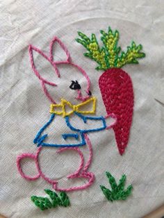 a close up of a embroidery on a piece of cloth with a bunny holding a carrot