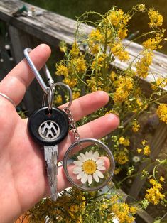 a hand holding a key chain with a peace sign on it and a daisy in the middle