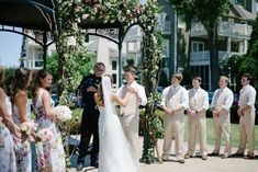 a bride and groom standing in front of their wedding party at the end of an outdoor ceremony