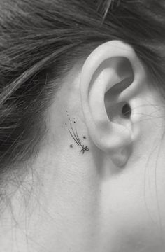 a woman's ear with a small dragonfly tattoo on her left behind the ear