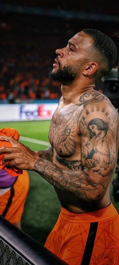 a man with tattoos on his chest holding a ball