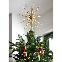 a star ornament hanging from the top of a christmas tree