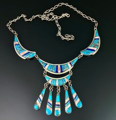 "This is one spectacular necklace!! It is such a flattering piece the way it drapes so beautifully on. The hook and open link chain give a lot a versatility in the wearable length and I have it hooked at difference lengths in each of my photos. The inlay clean and sharp with turquoise, lapis and either angel skin coral or spiny oyster. What I particularly love about the the turquoise in this, is that it has the natural matrix which you don't often see in inlay. This necklace is the kind of piece Unique Blue Turquoise Inlay Necklace, Collectible Blue Inlay Necklace, Southwestern Blue Turquoise Inlay Necklace, Southwestern Blue Necklace With Inlay, Southwestern Blue Inlay Necklace, Southwestern Style Blue Inlay Necklace, Native American Totem, Turquoise Squash Blossom, Angel Skin