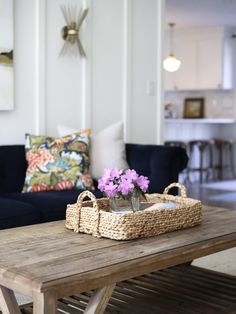 a living room with a couch, coffee table and flowers in a basket on it