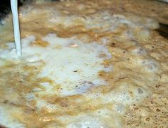 a pan filled with food and milk being stirred by a white spatula in it