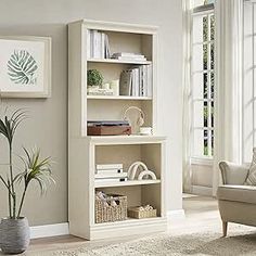 a living room with a couch, chair and bookshelf on the floor in front of a window