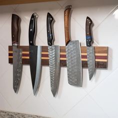 five knives are hanging on the wall in a kitchen