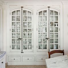 a white china cabinet with glass doors and drawers