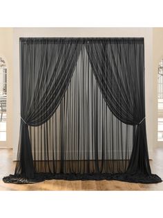 a black sheer curtain hanging on the side of a wall next to a wooden floor