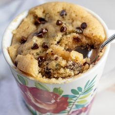 chocolate chip mug cake in a flowered cup with a bite taken out of it