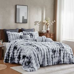 a bed covered in grey fur next to a window