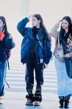 three young women standing next to each other in front of an airport terminal with their hands on their head