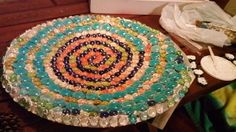 a table topped with lots of different colored beads on top of a wooden table next to a box