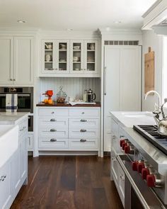 a kitchen with white cabinets and wood floors