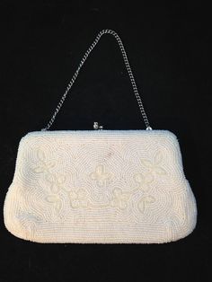 Vintage white beaded clutch purse made by an unknown maker. It is in good condition with no bead loss and patterned in a floral design. The interior is a white satin that is in need of a deep cleaning, various ink, dirt and make-up staining. The clasp is silver toned metal in a bead design and works well. The purse is 7 1/2 inches wide, 4 1/2 inches tall and opens to inches. The chain handle can be either on the outside and carried or can be folded into the clutch. the chain handle extends to 5 White Beaded Evening Bag For Formal Occasions, Formal Beaded Cream Evening Bag, Formal Cream Beaded Evening Bag, Formal White Beaded Evening Bag, Vintage White Evening Bag For Events, White Beaded Evening Clutch, Formal White Beaded Clutch, Classic White Evening Bag With Gold-tone Hardware, Vintage White Clutch For Events