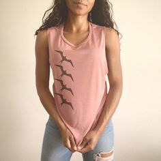 "Lele ka 'iwa mālie kai koʻo. \"When the ʻiwa bird flies (out to sea) the rough sea will be calm.\" Source: ʻŌlelo Noʻeau by Mary Kawena Pukui This comfortable muscle tank is soft and flowy with low cut armholes for a relaxed look. Get your sweat on with a good hula /ori tahiti workout. * 65% polyester/35% viscose* * Low cut armholes * Curved bottom hem * Side seams *Athletic Heather is 52% polyester/48% viscose; Black Heather is 80% rayon/20% polyester." Casual Beach Tank Muscle Tee, Casual Beach Muscle Tank Tee, Sleeveless Graphic Print Vacation Tops, Sleeveless Graphic Print Top For Vacation, Summer Cotton Tops With Flamingo Print, Summer Cotton Top With Flamingo Print, Cotton Top With Flamingo Print For Summer, Summer Cotton Tops With Bird Print, Casual Summer Tops With Bird Print