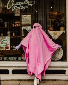 a mannequin wearing a pink cape in front of a store window