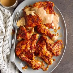 a plate with chicken wings covered in gravy next to a cup of coffee