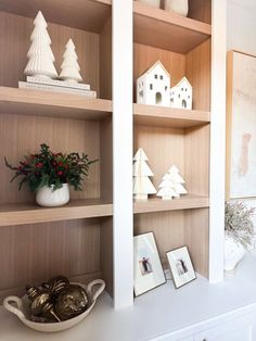 the shelves are decorated with christmas decorations and ornaments in white vases on top of them