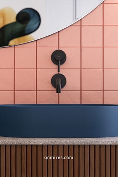 a bathroom sink sitting under a mirror next to a wall mounted faucet in front of a pink tiled wall