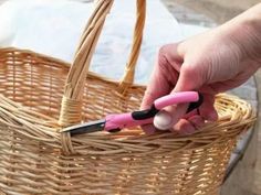 a person is holding a pink and black pen in a wicker basket on the ground