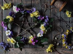 flowers are arranged in the shape of a star on a wooden table next to scissors and twine