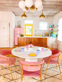 a kitchen with pink and yellow chairs around a white table