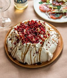 a cake with white frosting and pomegranates on it sitting on a plate