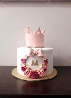 a white cake with pink flowers and a crown on top