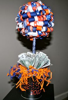 a money tree made out of dollar bills on top of a black table with orange and blue streamers