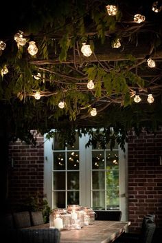 some lights are hanging from the ceiling above a table with candles and jars on it