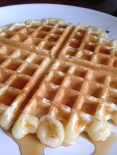 a waffle on a white plate with syrup drizzled over the top