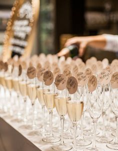 there are many wine glasses lined up on the table with name tags attached to them