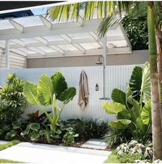 an outdoor shower surrounded by tropical plants and greenery on the side of a house