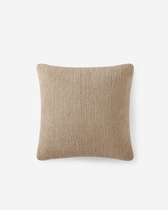 a beige pillow on a white wall