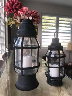 two lanterns are sitting on a table with flowers in them