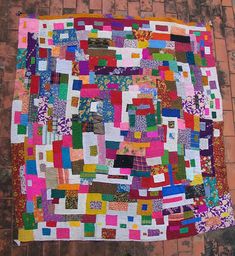 a colorful quilt hanging on the side of a brick wall