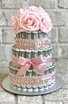 a cake made out of money with pink roses on top