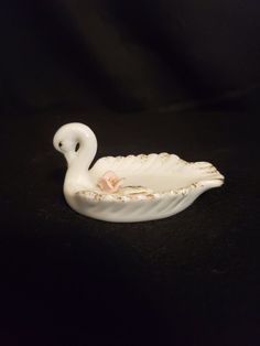 a white swan shaped bowl sitting on top of a table