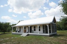 a small white house sitting on top of a lush green field