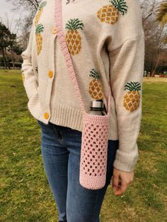 a woman wearing a pink crocheted purse with pineapples on the side