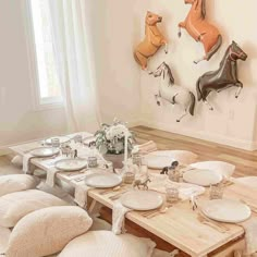 the table is set with white plates and place settings in front of an animal wall hanging