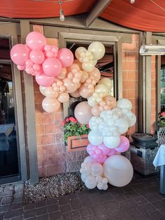 a bunch of balloons that are hanging from a ceiling in front of a building with windows