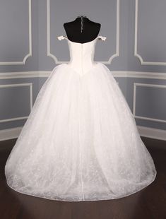 a white wedding dress on display in a room with blue walls and wood flooring