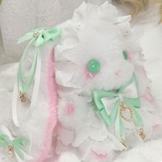 a white teddy bear with pink and green accents