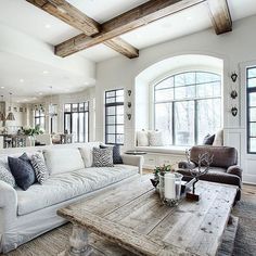 a living room filled with white furniture and lots of wood beams on the ceiling