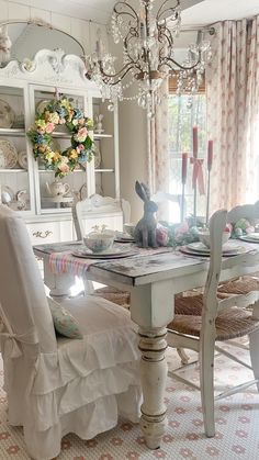 a dining room table and chairs in front of a china cabinet with flowers on it